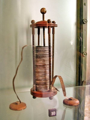 Voltova baterija z začetka 19. stoletja je sestavljena iz cinkovih in bakrenih diskov, potopljenih v slanico, ki jih ločuje klobučevina. Eno celico sestavljata sosednja diska. Fotografija: Daniele Pugliesi (CC-BY-SA)