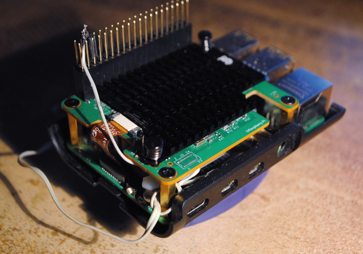 Raspberry Pi 5 z nameščenim Raspberry Pi AI HAT+ 2 in baterijo za uro realnega časa v improviziranem ohišju.